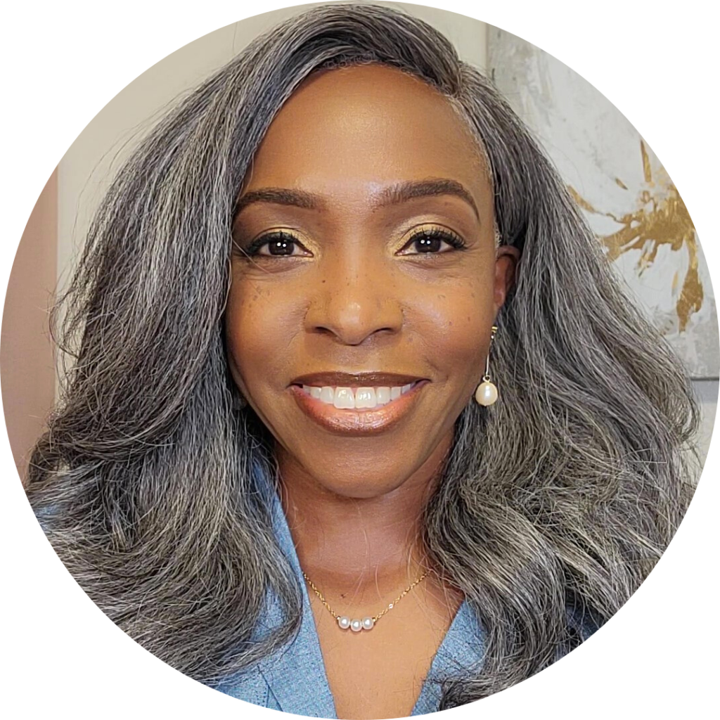Professional headshot of Kendra Lewis smiling, wearing a light blue blazer with gray hair and pearl jewelry